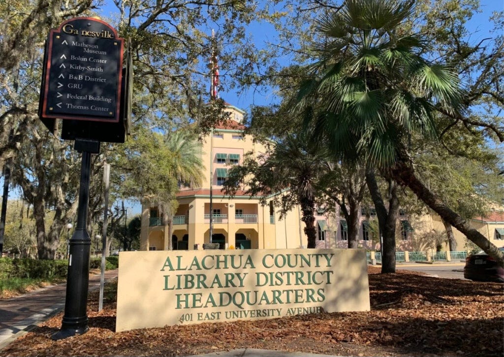 The street sign in front of an attractive two story building says "alachua County Library District Headquarters."