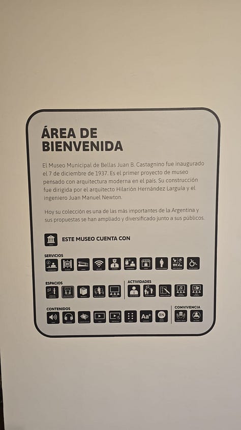 1- Fotografía de una cartelería externa de un museo, hecha de estructura de metal de aproximadamente unos tres metros de altura y sesenta centimetros de ancho. Se encuentra ubicado en el medio de un parque, en un sector donde hay tránsito peatonal. En la cartelería hay pictogramas que indican los espacios, servicios, contenidos y actividades de el museo castagnino 2- Fotografía de una cartel externa de un museo ubicado en el jardin previo al ingreso al edificio. El cartel es un rectángulo horizontal con un pie metalico que entra en el suelo. Da la bienvenida y expone pictogramas que indican los espacios, servicios, contenidos y actividades con los que cuenta el museo. 3- Fotografia de una pared en el interior de un museo. la pared esta pintada de negro y tiene en color blanco la leyenda con el nombre dle museo nacional del grabado y un texto. Al costado derecho hay un listado de pictogramas que indican los espacios, servicios, contenidos y actividades con los que cuenta el museo. 4- Fotografia de una pared en el interior de un museo. la pared es blanca y tiene en el centro un recuadro con borde negro y en su interior un texto que da la bienvenida. Debajo hay un listado de pictogramas que indican los espacios, servicios, contenidos y actividades con los que cuenta el museo. 5- Fotografia de un sector de una exhibición. En la pared hay cuatro imagenes enmarcadas y debajo en un exhibidor hay folios aillados con documentos antiguos y otras imagenes. En un costado se encuentra un pictograma y un código qr. 6-Fotografia de una sala de exhibición de un museo de arte contemporaneo. En el centro hay una mujer de pie agarrando el celular con las dos manos para sacar una fotografia a un dispositivo que hay en una de las paredes de la exhibición. detrás de ella, al final de la sala hay mas personas de pie y sentadas.