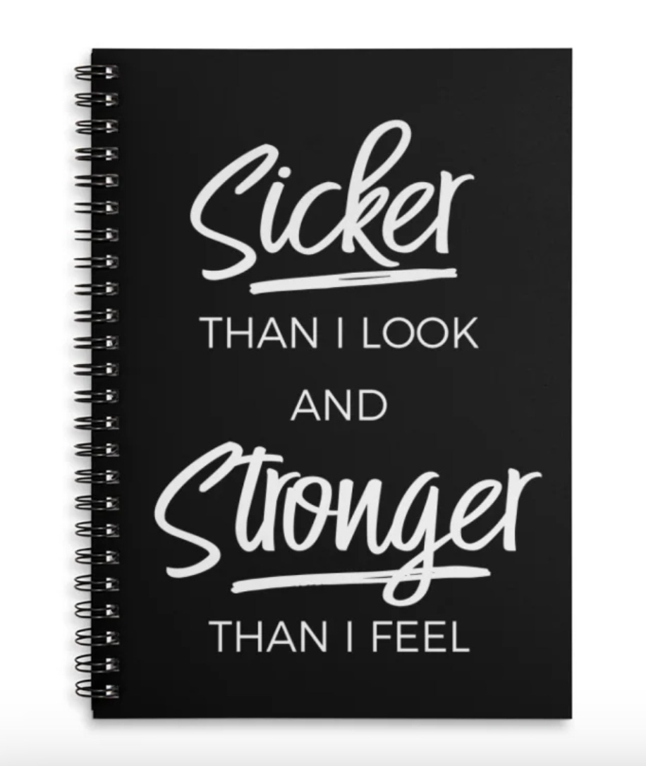 Black spiral notebook with handwritten-style white text on the cover reading, "sicker than I look and stronger than I feel."