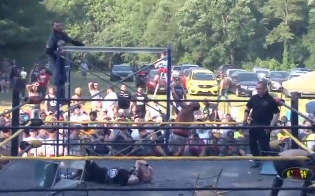 [Screenshot: Devon Moore climbs onto the scaffold while G-Raver has an existenial crisis on the mat]