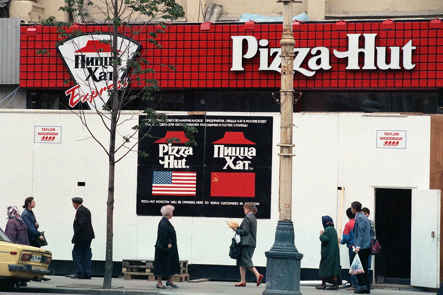 A Pizza Hut also has signage in Cyrillic lettering and people in coats and babushka scarves are walking by. 