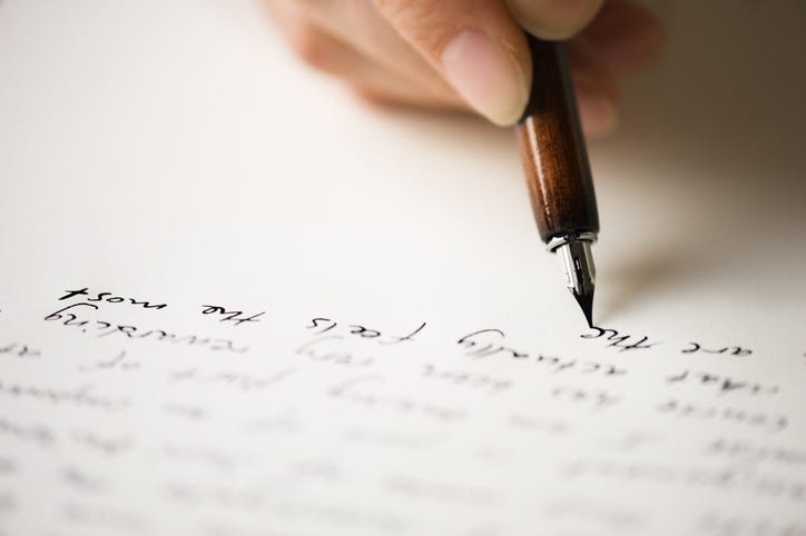 using fountain pen to write words on paper