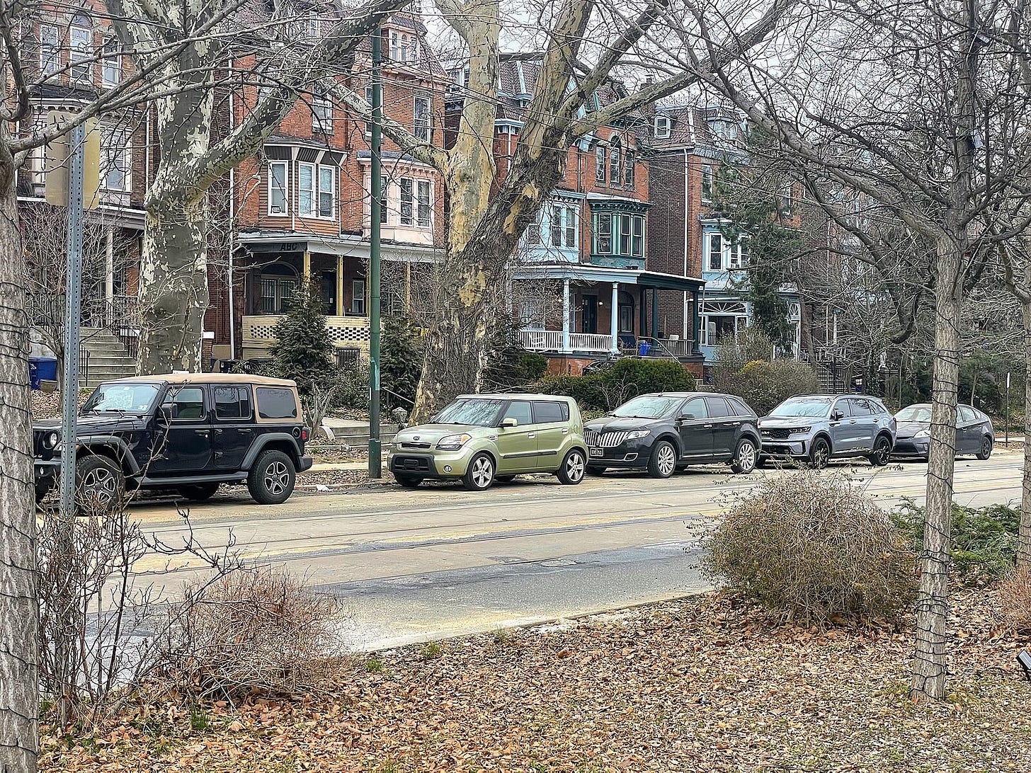 photo of homes on a tree-lined street in the city with parked cars and a median photo of homes on a tree-lined street in the city with parked cars and a median