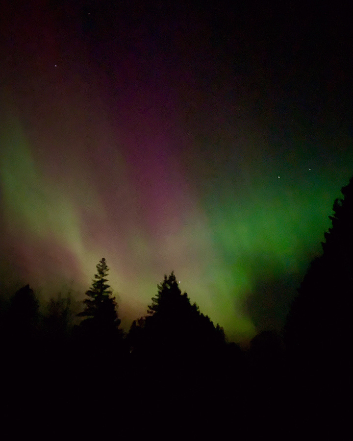 Photo one shows green and pink lights from Aurora borealis. Photo two shows green lights behind an old farmhouse at night.