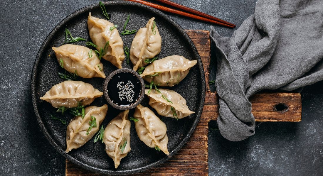 Gyoza served with soy sauce and garnished with green onions