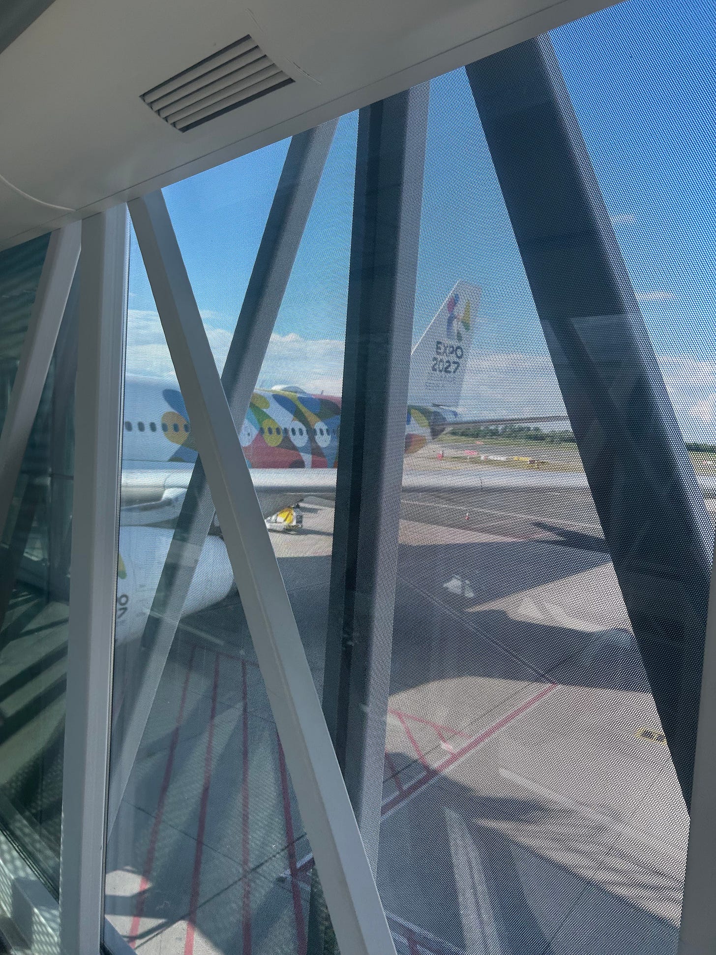 An Air Serbia jetliner, as viewed from the jet bridge. It is adorned with an advertisement for Expo 2027, to be hosted in Belgrade.