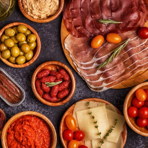Typical spanish tapas concept. Concept include slices jamon, chorizo, sausage, bowls with olives, tomatoes, anchovies,  mashed chickpeas, cheese. Typical spanish tapas concept. Concept include slices jamon, chorizo, sausage, bowls with olives, tomatoes, anchovies,  mashed chickpeas, cheese. Top view. Sevillo Fine Foods stock pictures, royalty-free photos & images