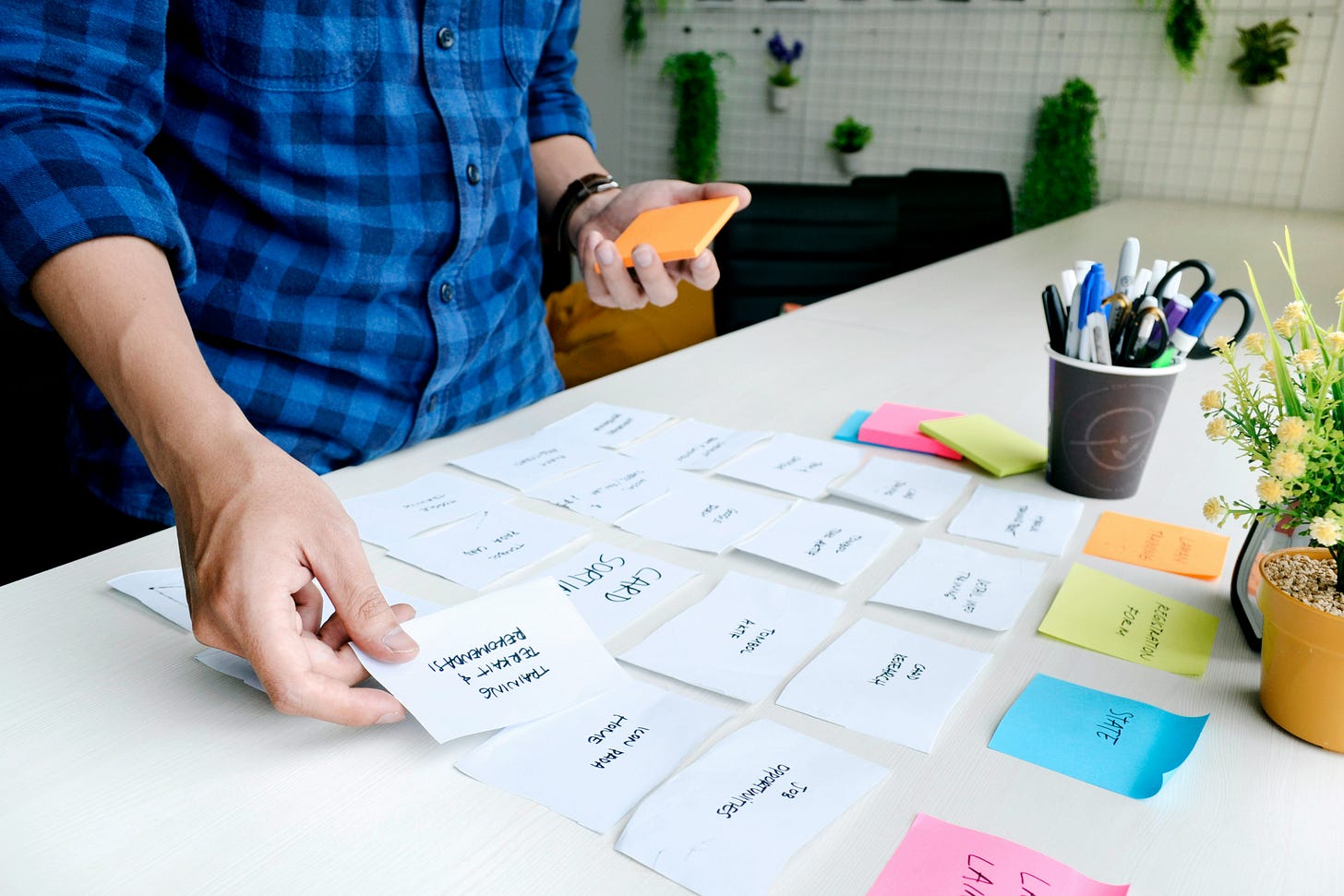 A person organizing various colored sticky notes on a wall, representing the way AI models categorize user data and demographics.