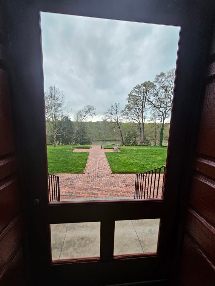 Views from a tall pained window with a candle and out a screen door.