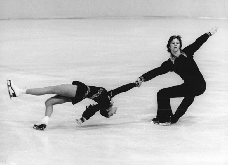 BLack and white photo of two figure skaters doing the classic death spiral move