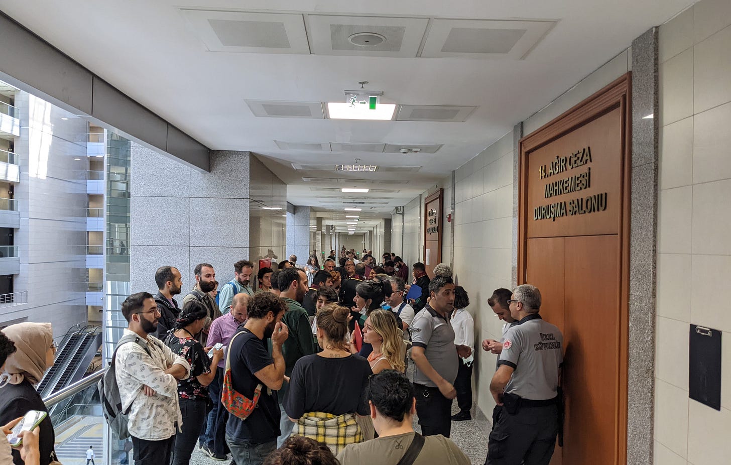 Adliyede, duruşma salonunun önünde bekleyen bir kalabalık.