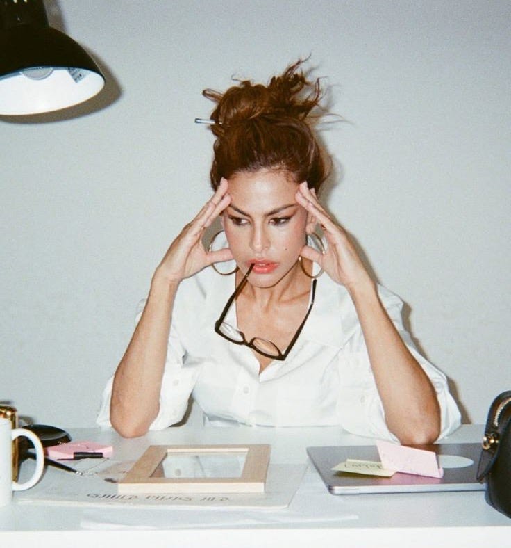 This may contain: a woman sitting at a table with her head in her hands