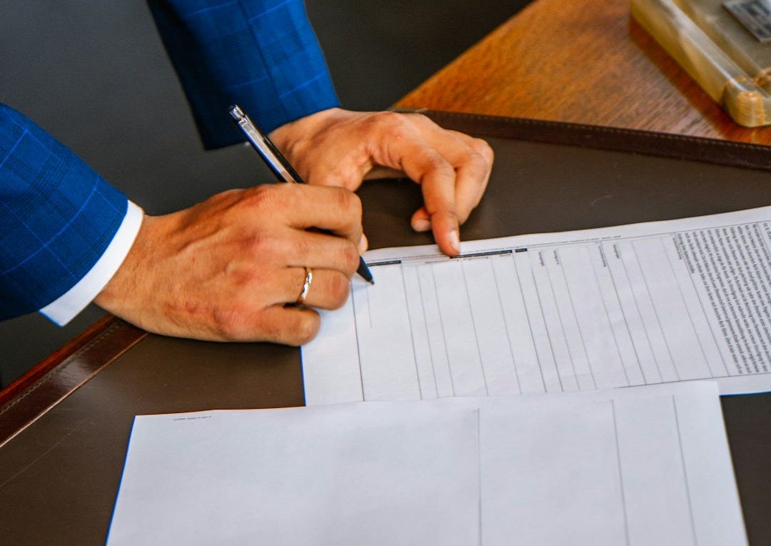 person writing on white form paper