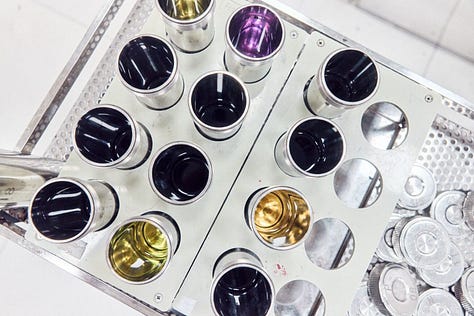 A gallery of three images which show: a top-down view of metal recepticles with colourful liquids inside, a green shiny screen with the words LORE in the middle, and a brightly lit room that has the words "Rebuild. European Social Platform" printed on a white wall in front of red stools.