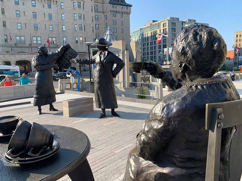 Photo of bronze sculptures of the Famous Five in a circle – some sitting on chairs and some standing