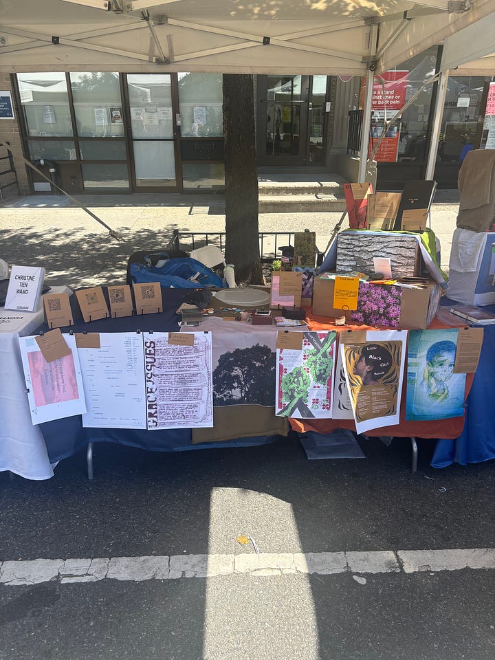 5 Black people standing behind the exhibitor booths smiling and posing at the festival.