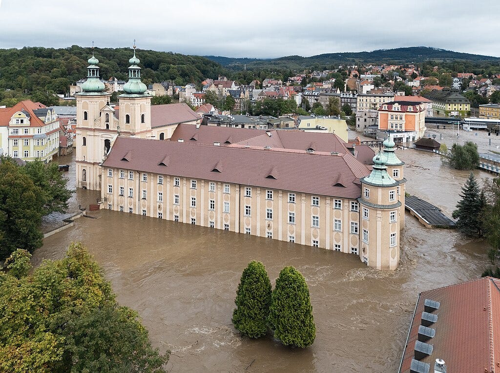 Aerial photograph of floodwaters surrounding and flowing through a large Gothic monastery in Poland. 