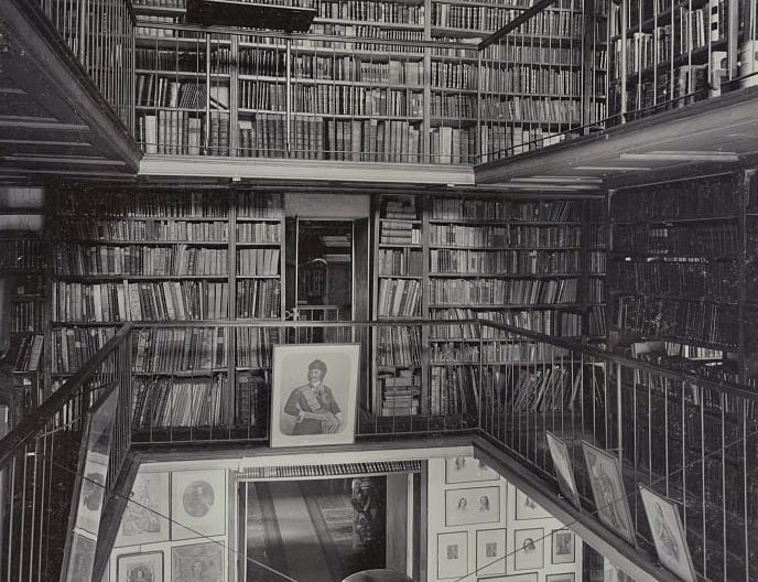 Photograph shows several levels of books and framed portraits at the Imperial Public Library, now National Library of Russia.