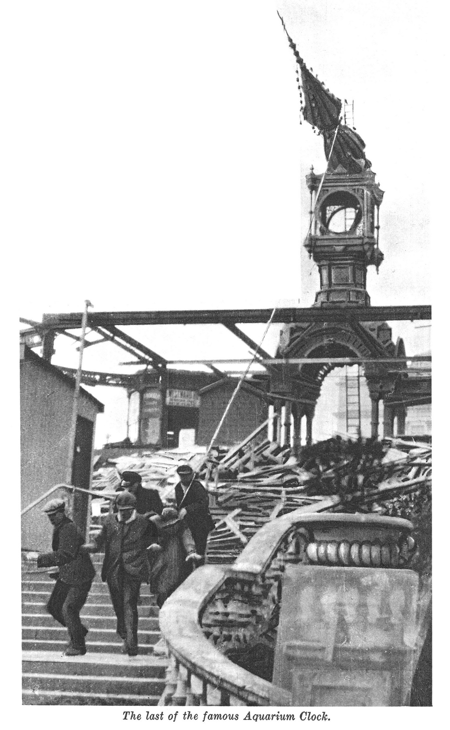 A gothic style clock tower being demolished by a group of men.