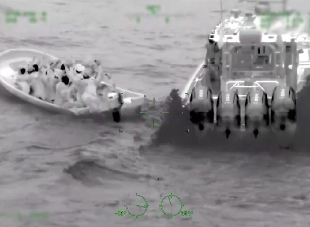 A CBP boat pulls up alongside a cartel smuggling vessel with sixteen aboard in the Caribbean