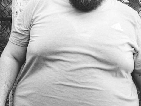 a man with a beard standing in front of a fence a man with a beard standing in front of a fence