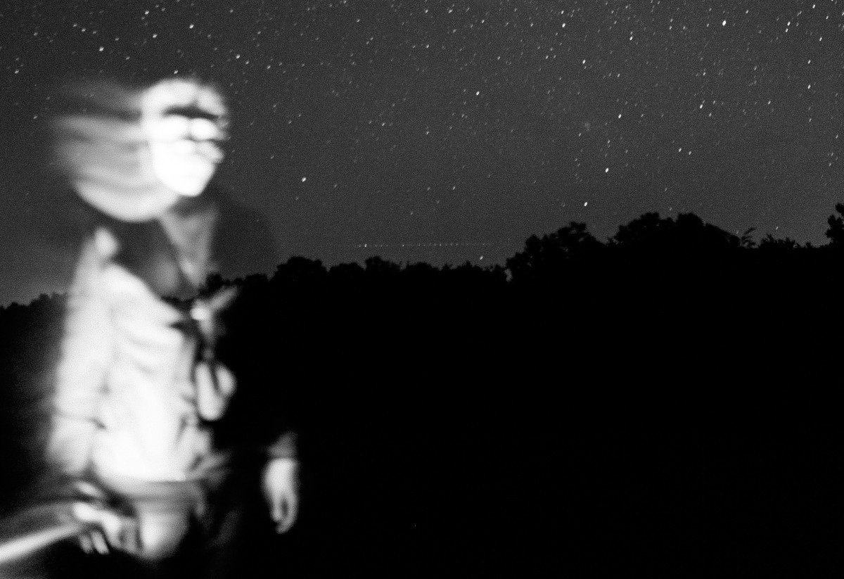 black-and-white image outdoors at night featuring a ghostlike entity