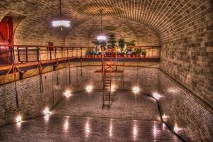 A swimming pool in a brick building with a ladder.