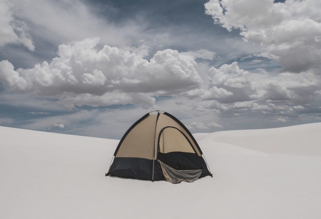 a tent in the middle of a desert under a cloudy sky a tent in the middle of a desert under a cloudy sky