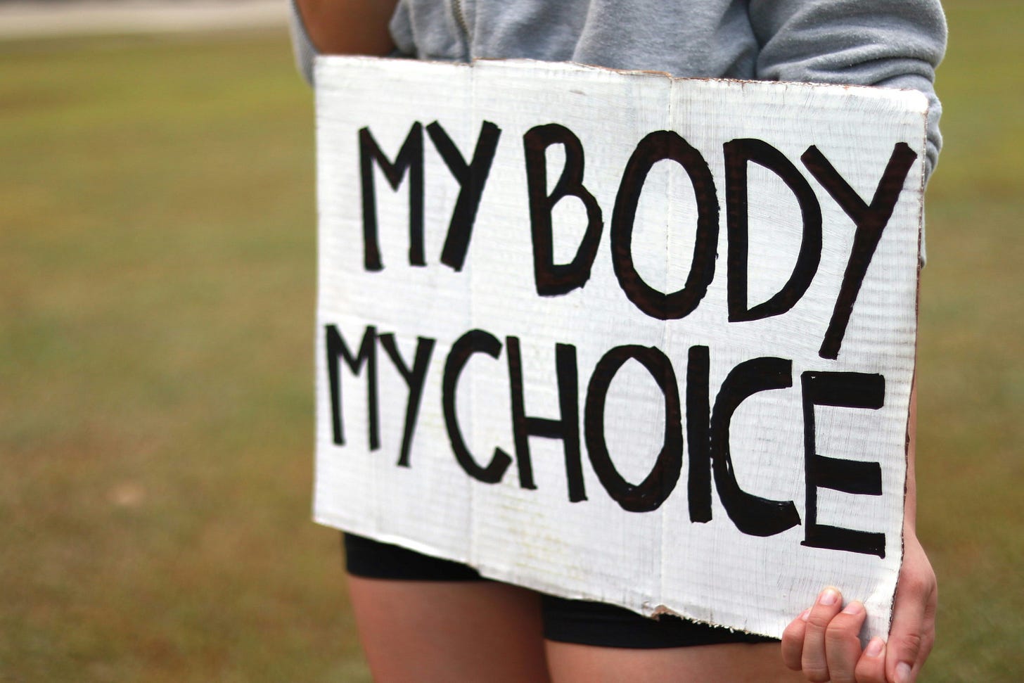A woman holding a sign saying "my body my choice"