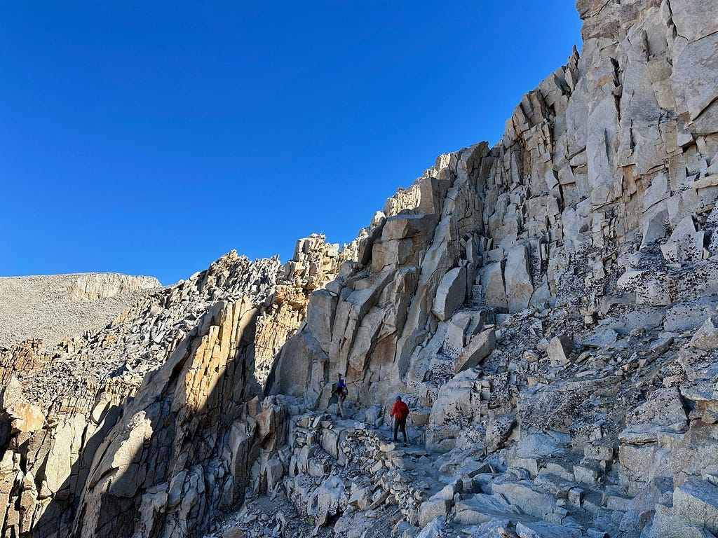 View of hikers on Whitney’s backside where the air gets thin and the trail narrows