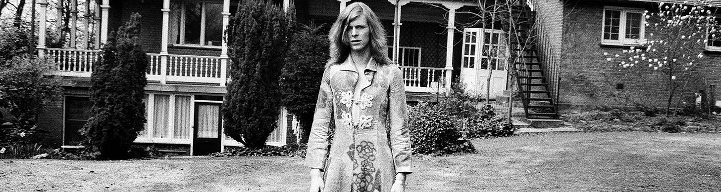 A black and white shot of David Bowie in a dress designed by fashion designer, Mr Fish