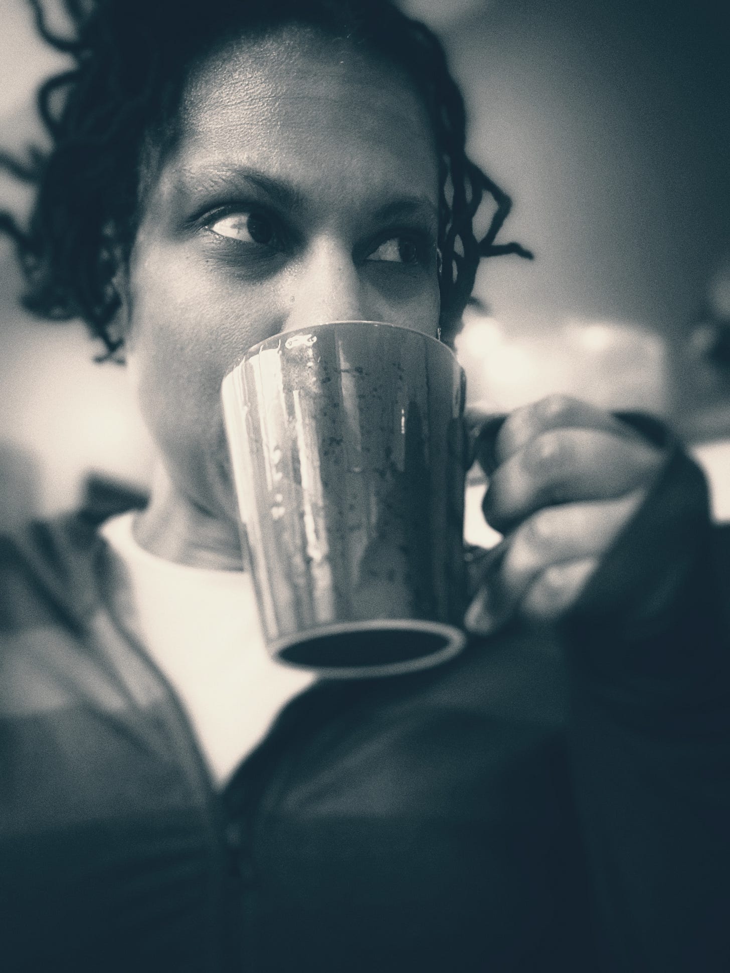 The picture is in black and white with Sandra's face and short locs. She drinks from a mug up to her lips. Her eyes look to the right.
