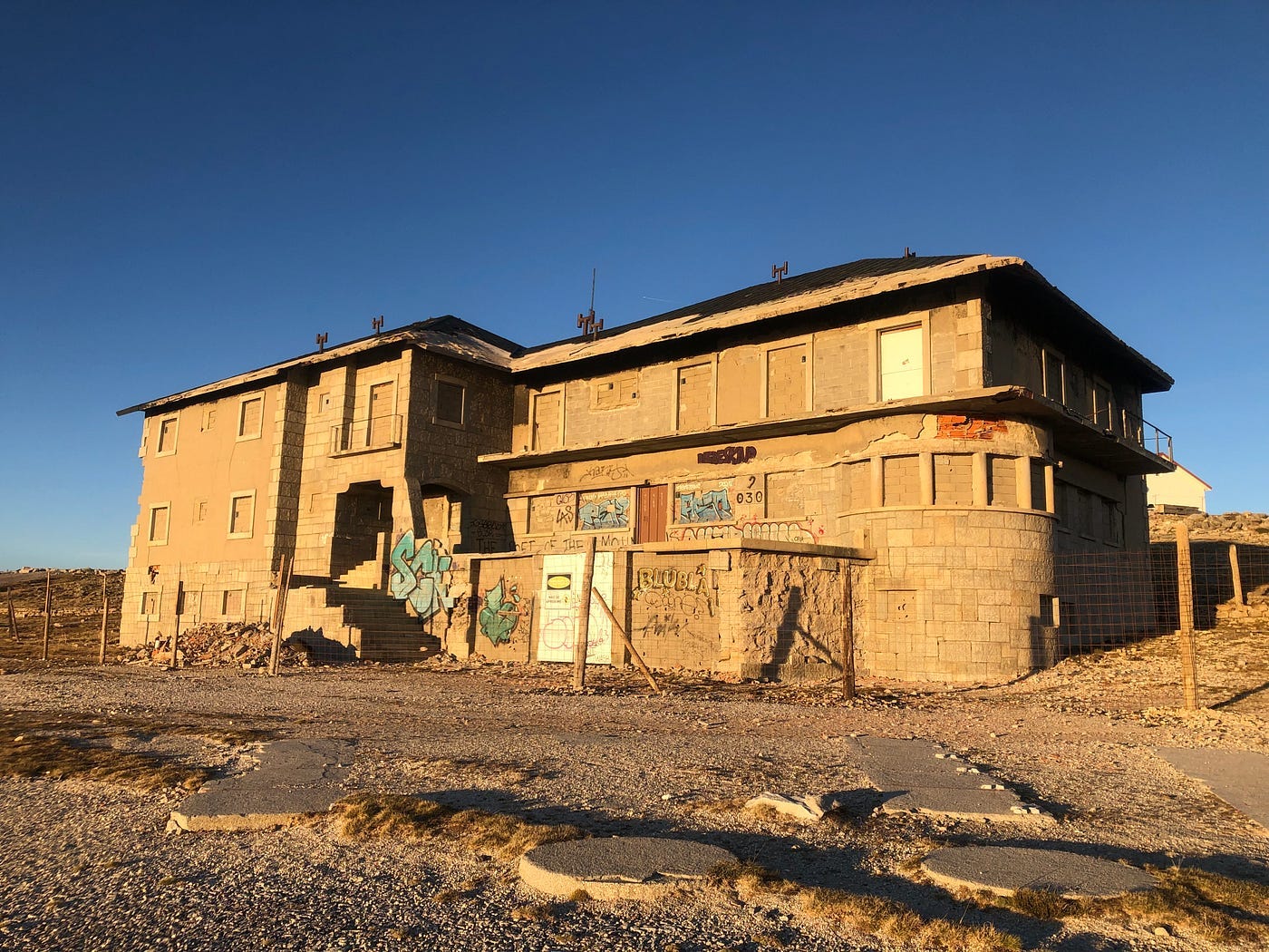 An abandoned, crumbling mountian-top military outpost, bathing in the low afternoon sun against a clear blue sky. An abandoned, crumbling mountian-top military outpost, bathing in the low afternoon sun against a clear blue sky.