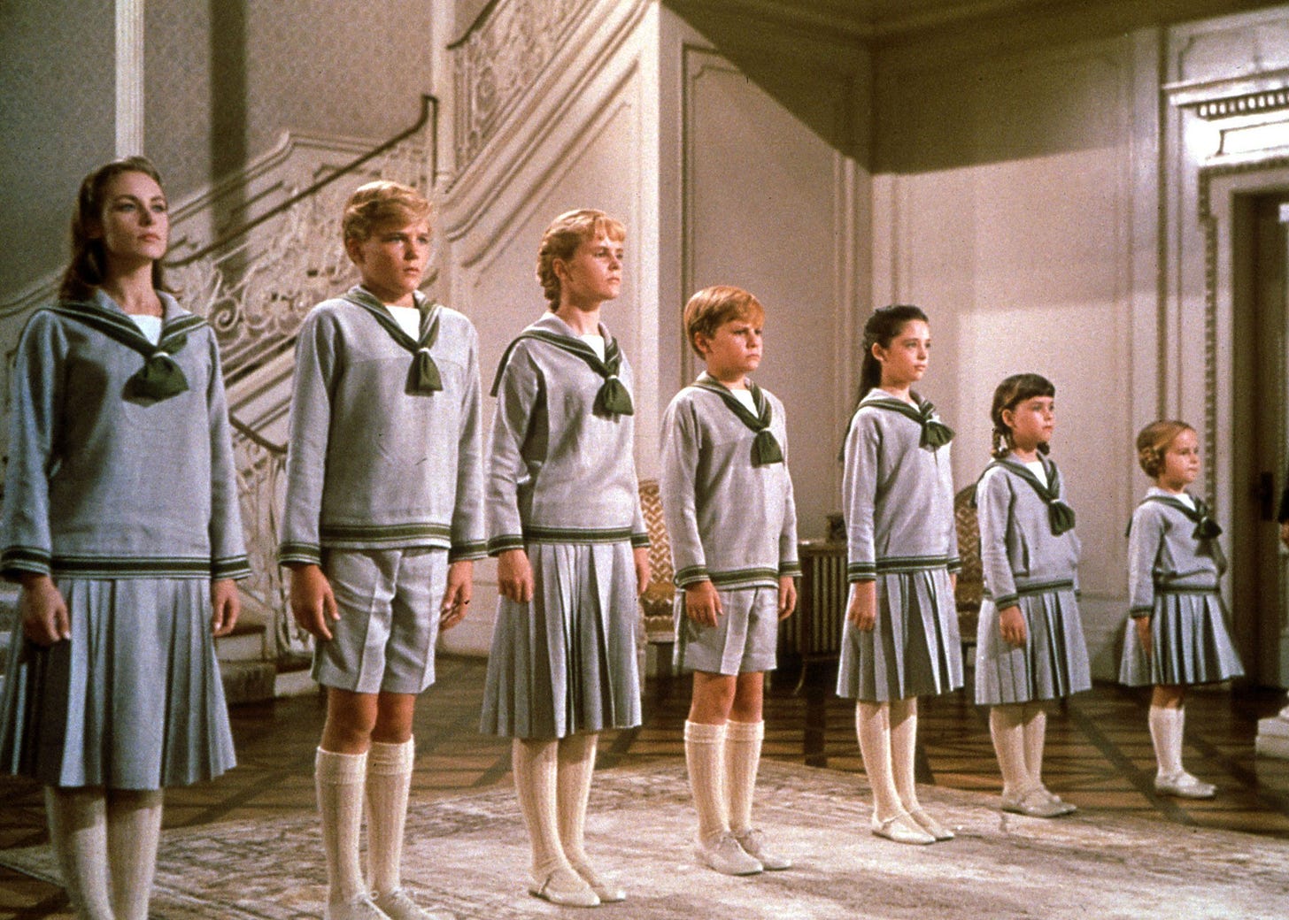 A still from the movie The Sound of Music with the children singing in a line