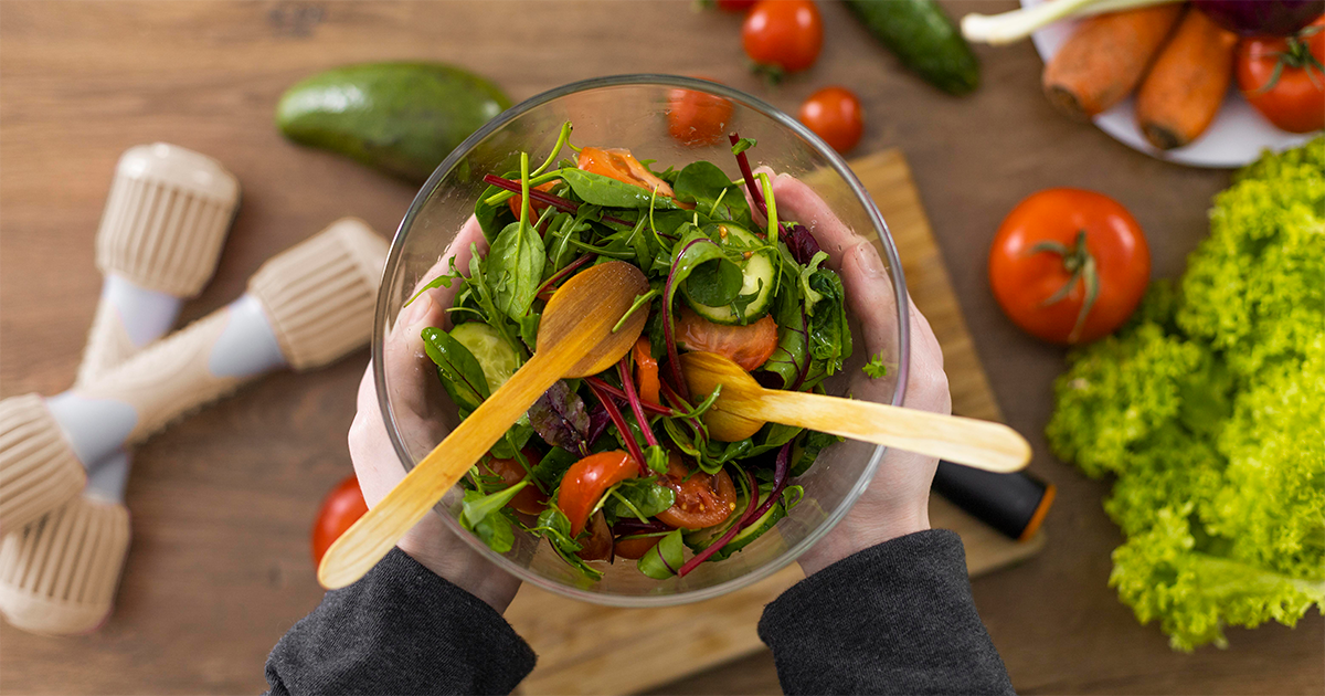 Imagem de um par de mãos segurando um prato de saladas Imagem de um par de mãos segurando um prato de saladas