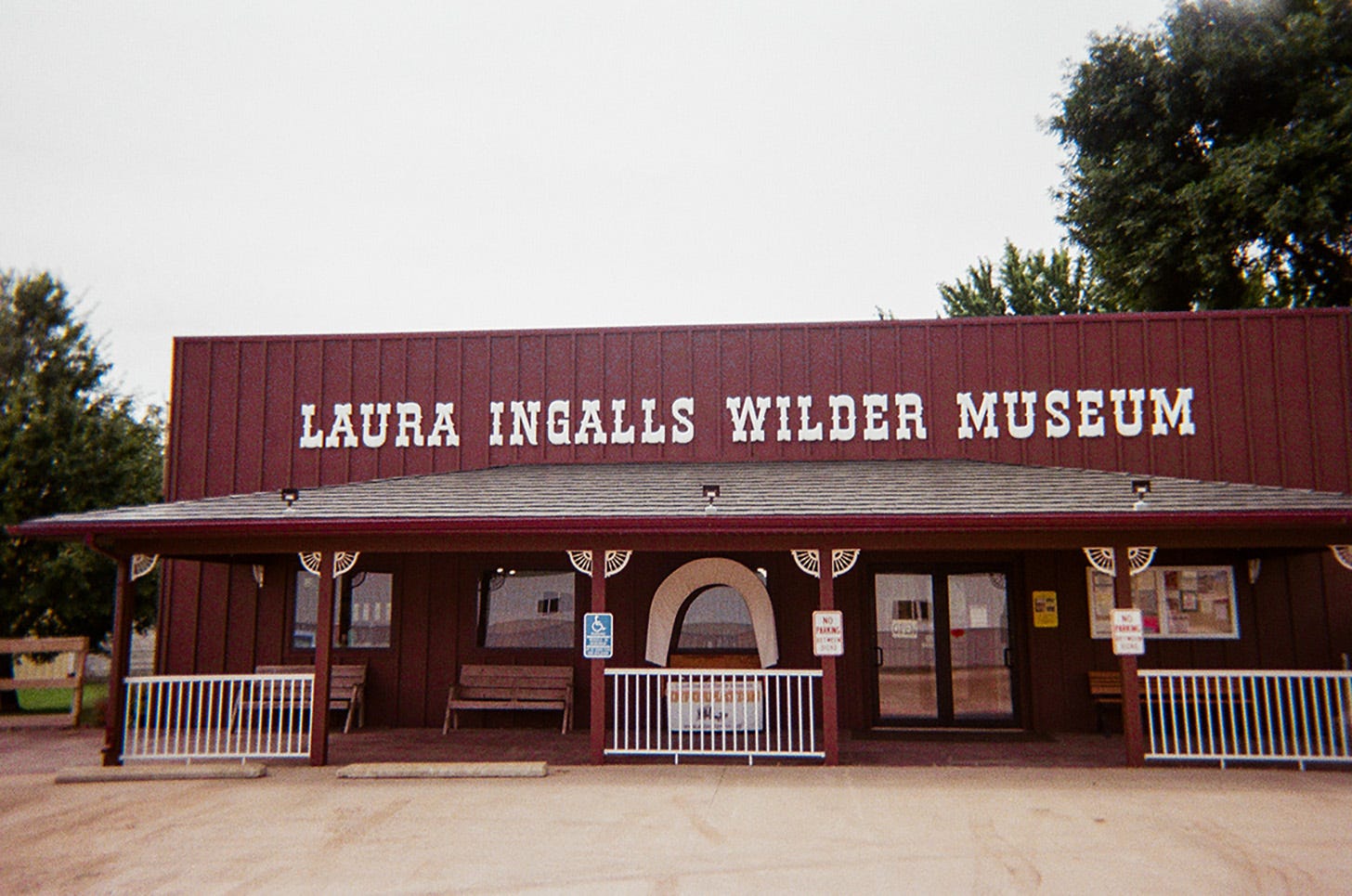 The brown exterior of the Laura Ingalls Wilder Museum with a display in the middle that looks like the back of a covered wagon.