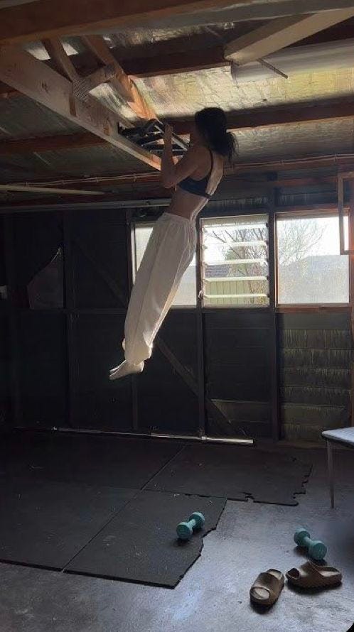This may contain: a woman hanging upside down in an empty room