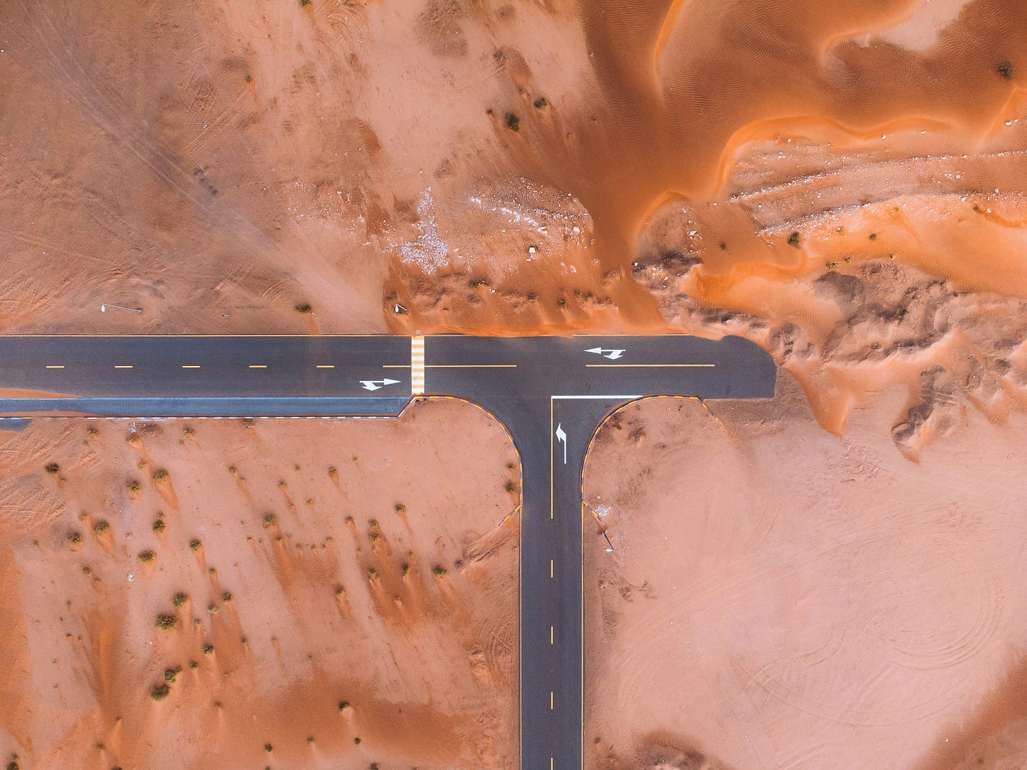 Aerial photo of two intersecting dead end roads in the middle of a barren desert.