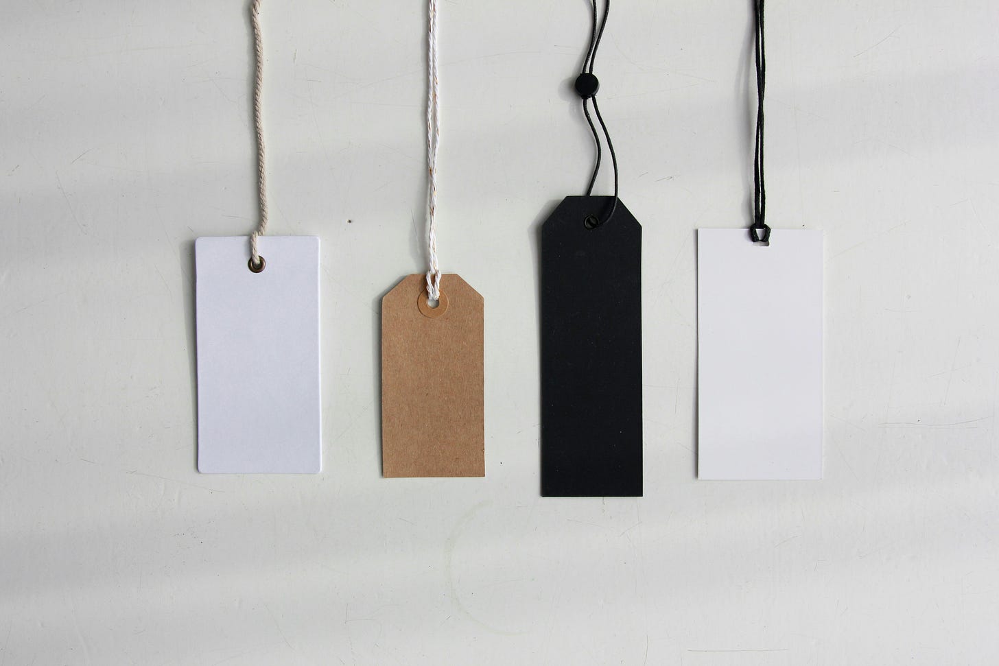 Four blank labels are laid on a white smooth surface. Four blank labels are laid on a white smooth surface.