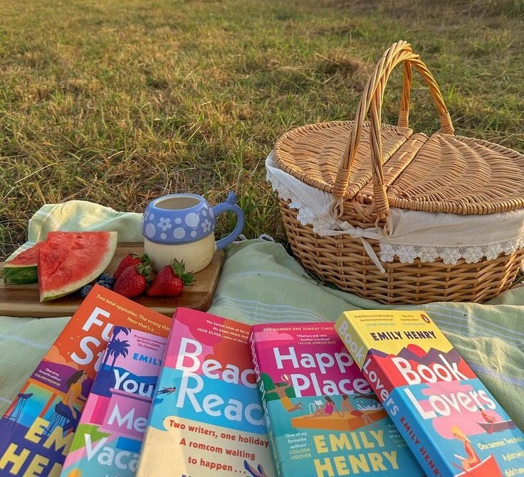 This may contain: some books and a basket on a blanket in the grass with watermelon slices