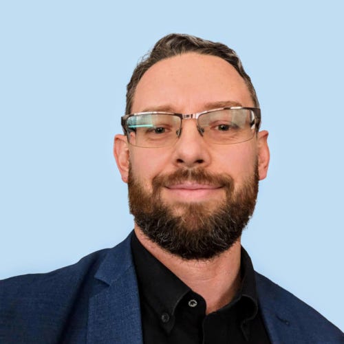 Headshot of Michael Plis, Cyberkite founder, smiling and wearing glasses.