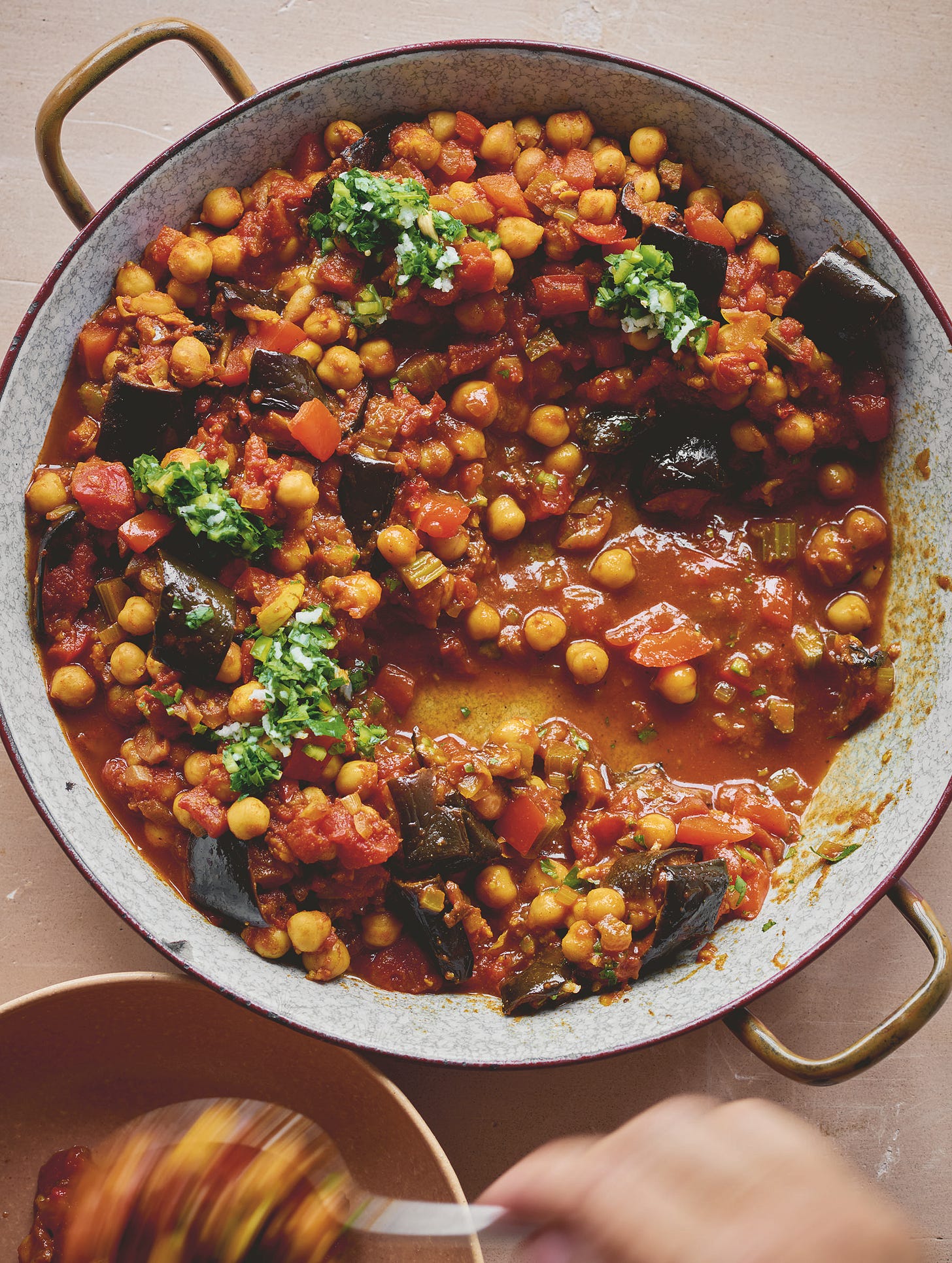 Dutch oven of eggplants stewed with chickpea and tomato with green lemon herb sauce.