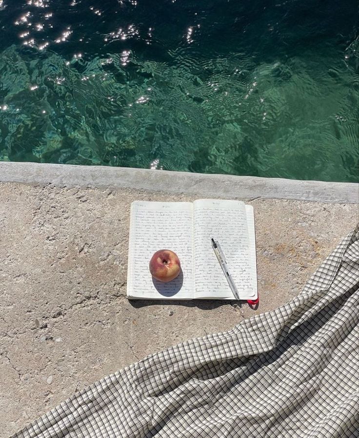 This may contain: an apple is sitting on top of a book next to the water with a pen in it