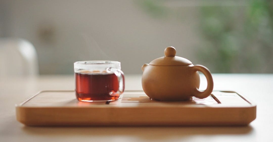 clear glass cup with tea near brown ceramic teapot