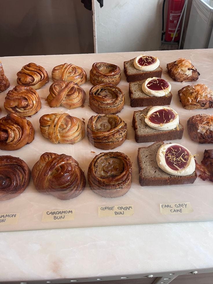 This may contain: there are many different types of pastries on the counter top, including breads and croissants