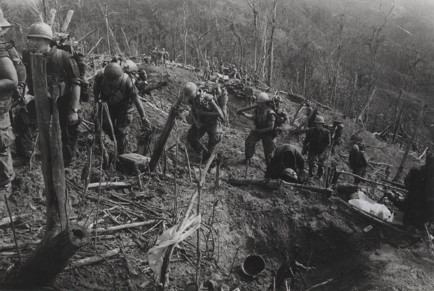 Marines climbing a steep, battle-scarred ridgeline in Vietnam.