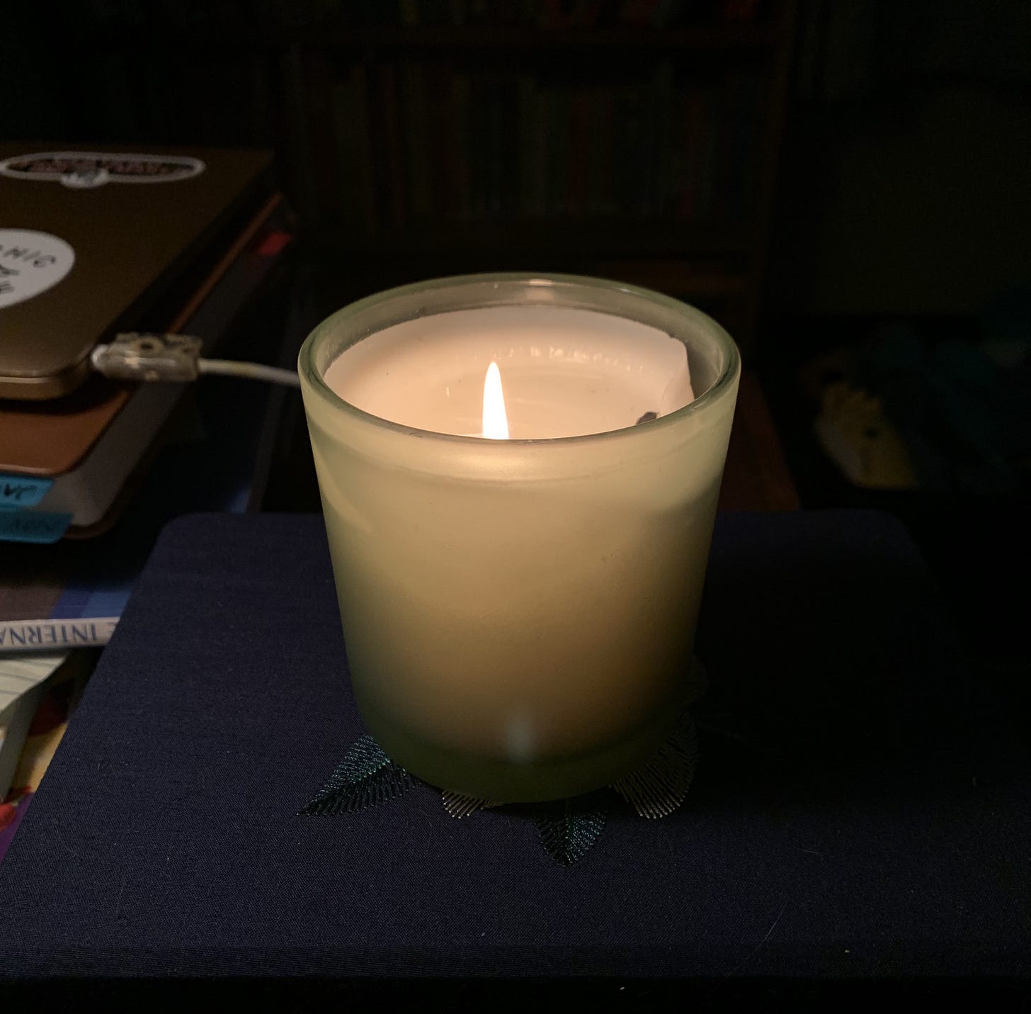 A lit pillar candle glowing golden in a darkened room.