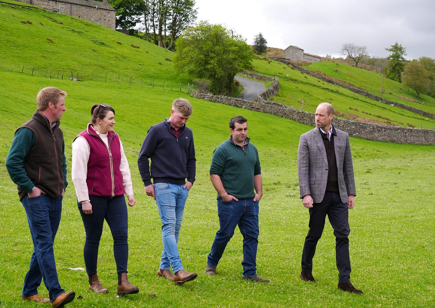 Prince William walking on the grass with a group of farmers