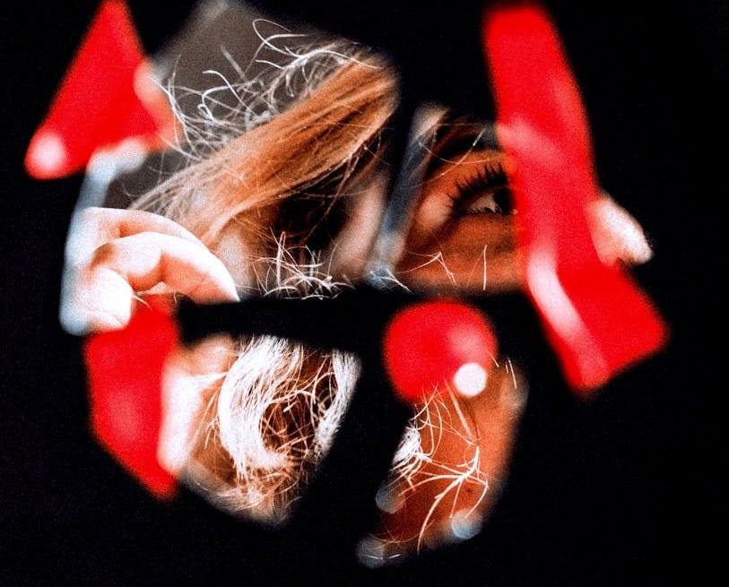 the reflection of a woman's face in a shattered mirror, with red bits around the reflection of a woman's face in a shattered mirror, with red bits around