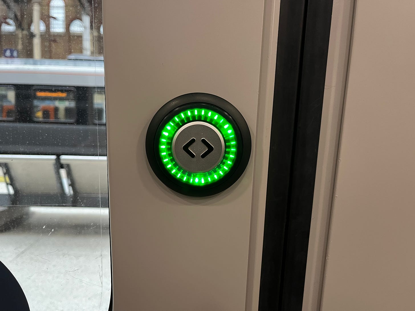 Photo showing a door open button on a London Overground Class 710 train illuminated in green.